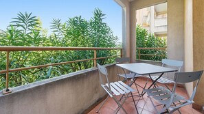 Een balkon met een tafel en stoelen, omringd door groen.