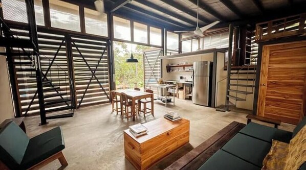 A spacious living area with a dining table, sofas, and a kitchen in the background.