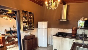 A kitchen with a refrigerator, stove, and a chandelier. - Pousada Jardim Colonial (Tiradentes)