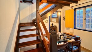 A wooden staircase leading to a dining area with a table and chairs. - Pousada Jardim Colonial (Tiradentes)