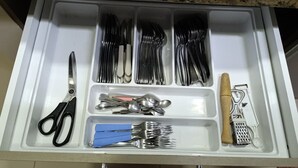 Un cajón con cubiertos, incluyendo tenedores, cuchillos y cucharas, organizados en compartimentos.