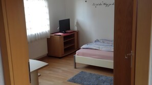 Une chambre à coucher comprenant un lit, un bureau, un téléviseur posé sur un meuble, un radiateur et un mur décoré d’une étoile.
