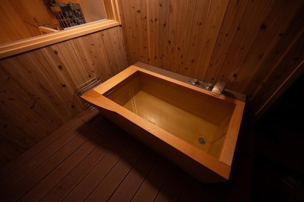 A wooden bathtub in a room with wooden walls and floor.