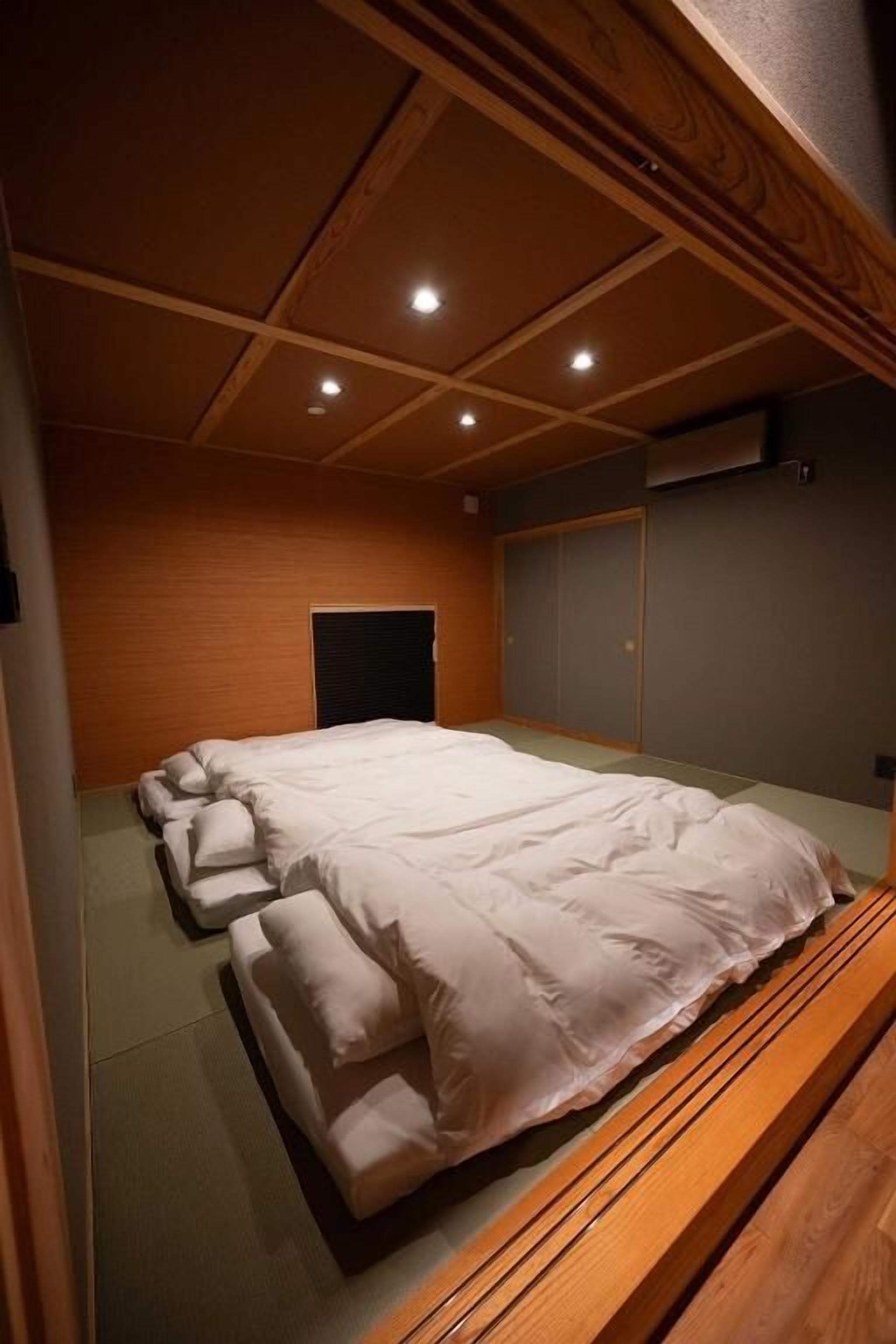 Een kamer met een groot bed, houten plafond en een schuifdeur.