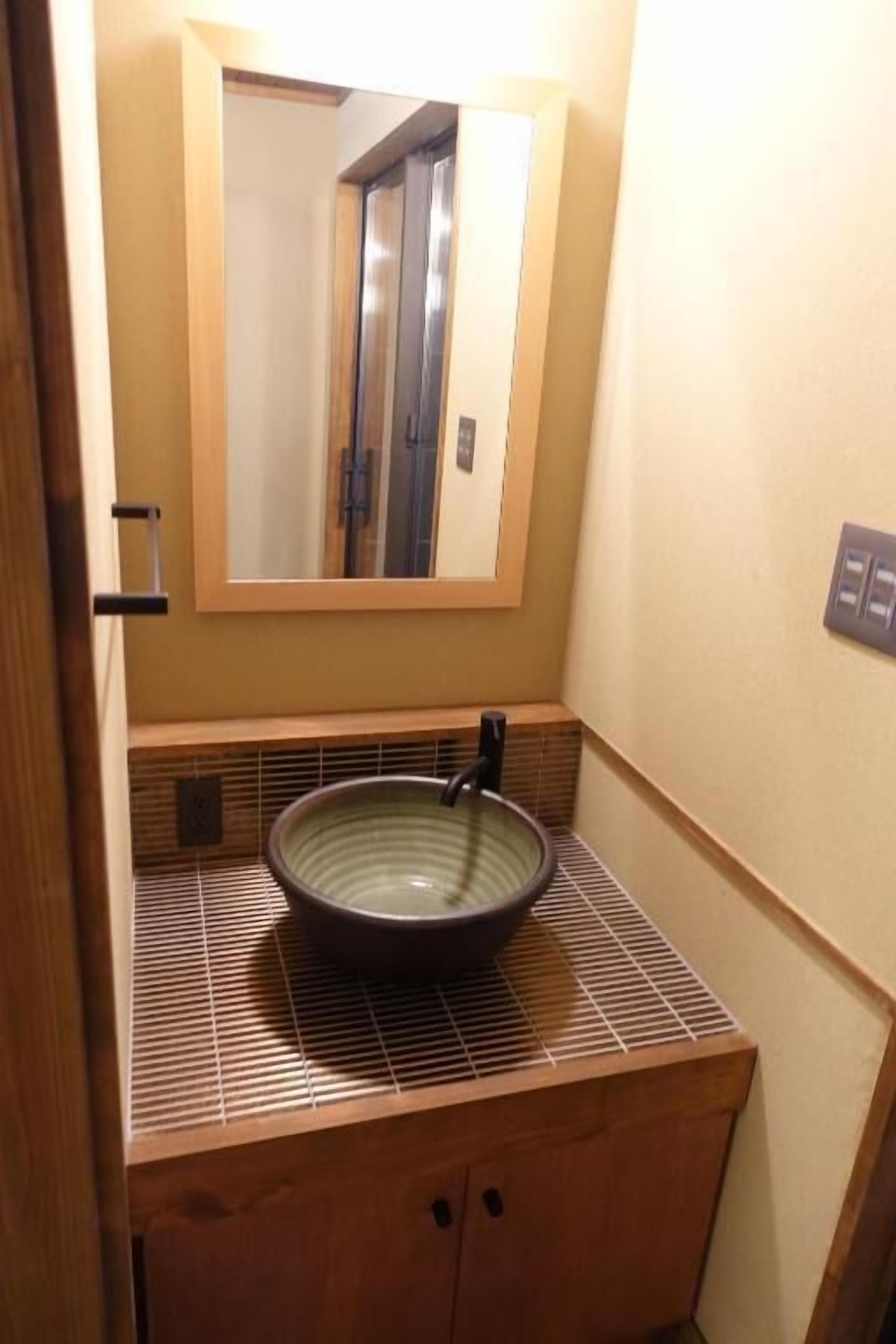 A bathroom with a large mirror, a bowl sink, and a wooden vanity.