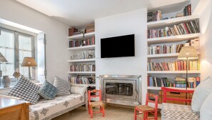 Una sala de estar acogedora con chimenea, estanterías, televisor y sofá.