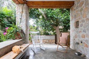 Une terrasse extérieure avec un banc en bois, un fauteuil à bascule et un fauteuil rembourré.