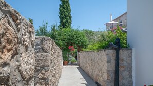 Un estrecho callejón con paredes de piedra, una planta en maceta y una estatua.