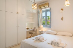 Une chambre d’hôtel avec un lit, un bureau, une chaise, une fenêtre avec des rideaux et une lampe suspendue.