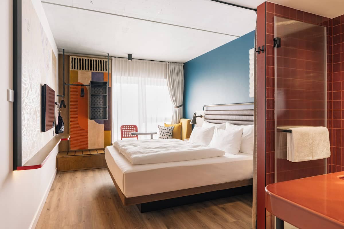 Una camera d'albergo con un letto, una doccia, un tavolino e una sedia.