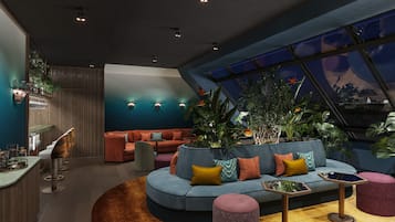 Eine moderne Lounge mit einer gebogenen Couch, einem runden Couchtisch und einer Bar mit Hockern.