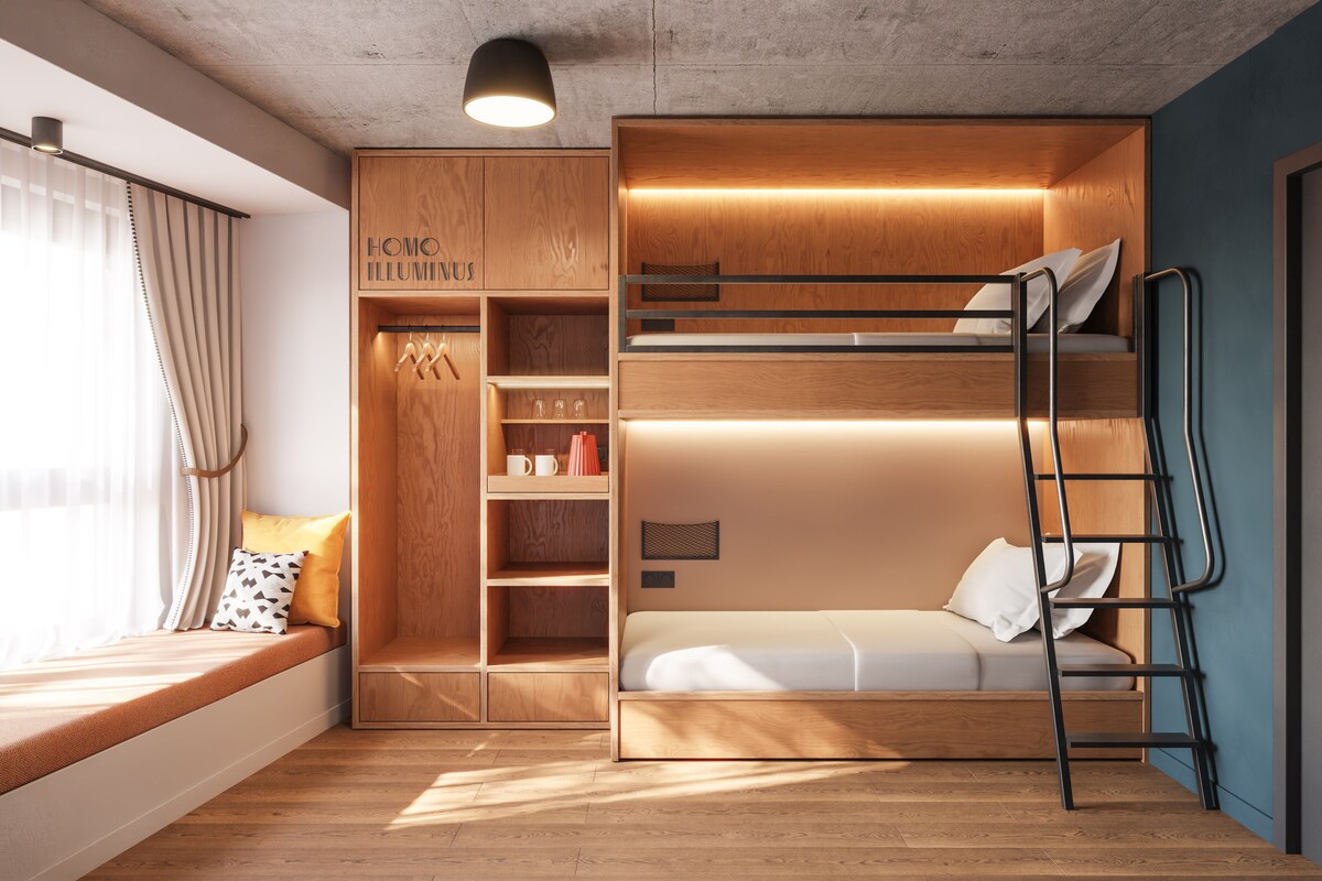 A compact room with a bunk bed, built-in wardrobe, and a seating area by the window.