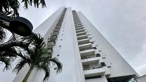 A tall, modern building with a grid-patterned facade and balconies.