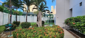 A courtyard with a large tree, a green mailbox, and a white building with a tiled exterior. - Beach Class Conselheiro Residence (Recife)