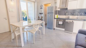 A modern kitchen with a dining area, including a table and chairs, a refrigerator, oven, and a sink. - Profumo di Rosa - One Bedroom Apartment, Sleeps 4 (Desenzano del Garda)