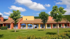Un hotel con una fila de habitaciones, asientos al aire libre y un césped bien cuidado.