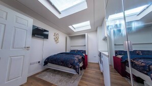 Camera da letto con lucernari, un letto, una TV e un armadio.