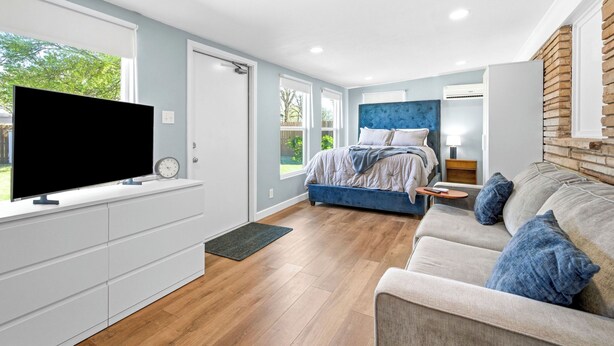A modern bedroom with a bed, a TV, and a sofa. - NEW 4BR Home Nearby ACU & Downtown - Family Vacation - Summer Savings- Sleeps 10 (Abilene)