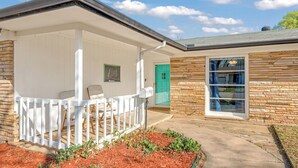A house with a porch, a stone exterior, a green door, and a window with a view. - NEW 4BR Home Nearby ACU & Downtown - Family Vacation - Summer Savings- Sleeps 10 (Abilene)