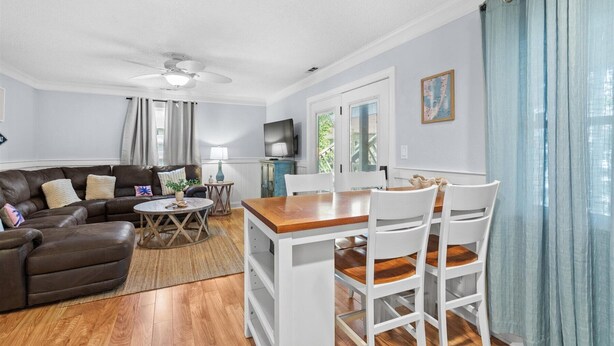 A living room with a sofa, a dining table with chairs, a ceiling fan, and a television. - Sonesta III 202 by Seaside Vacations & Sales (Ocean City)