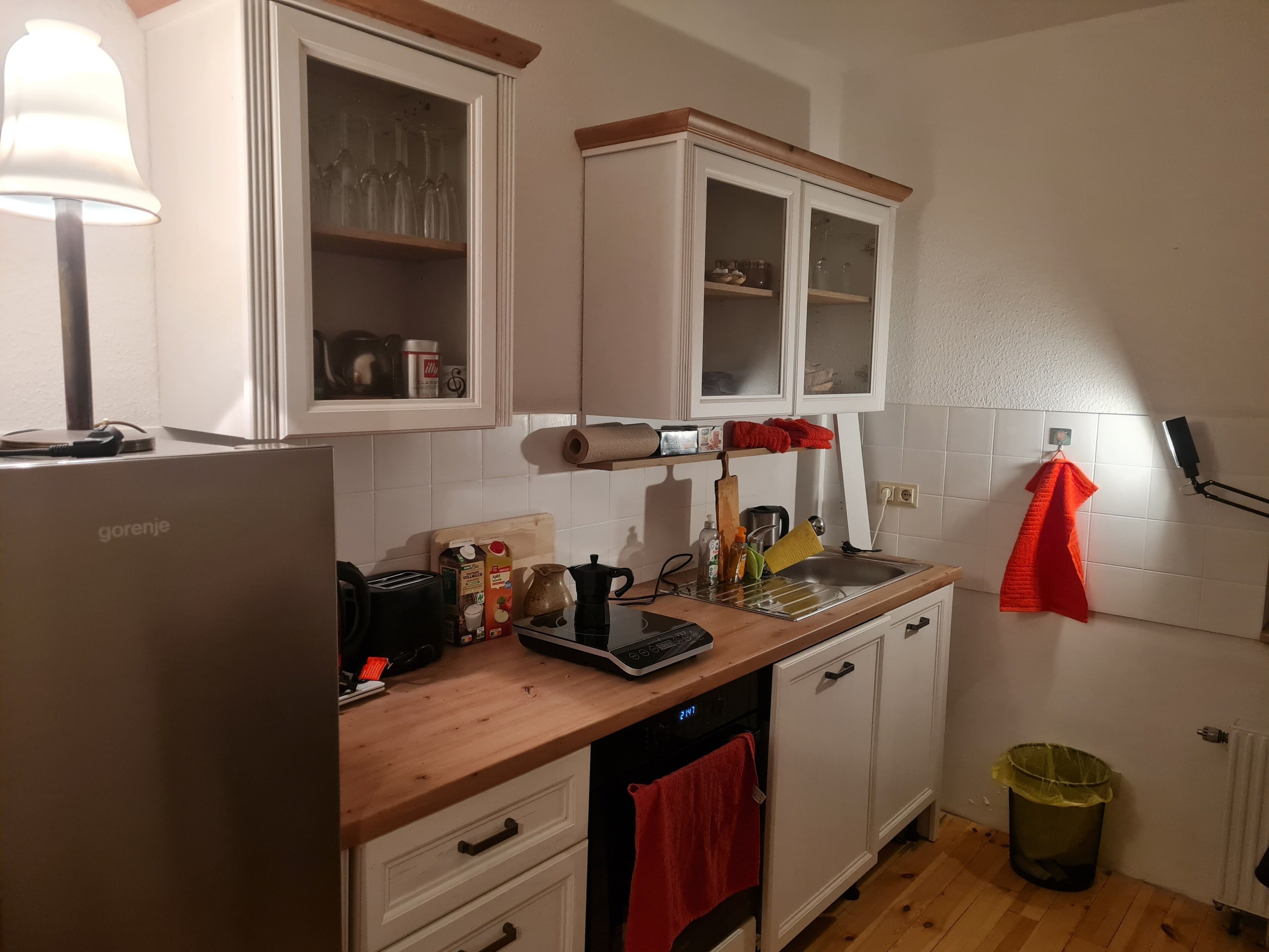 Eine Küche mit weißen Schränken, einer Holzauskleidetheke, einer Kaffeemaschine, einem Toaster und einem Spülbecken.