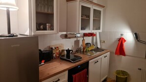 Eine Küche mit weißen Schränken, einer Holzauskleidetheke, einer Kaffeemaschine, einem Toaster und einem Spülbecken.
