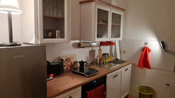 Eine Küche mit weißen Schränken, einer Holzauskleidetheke, einer Kaffeemaschine, einem Toaster und einem Spülbecken.