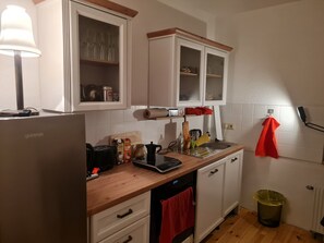 Eine Küche mit weißen Schränken, einer Holzauskleidetheke, einer Kaffeemaschine, einem Toaster und einem Spülbecken.