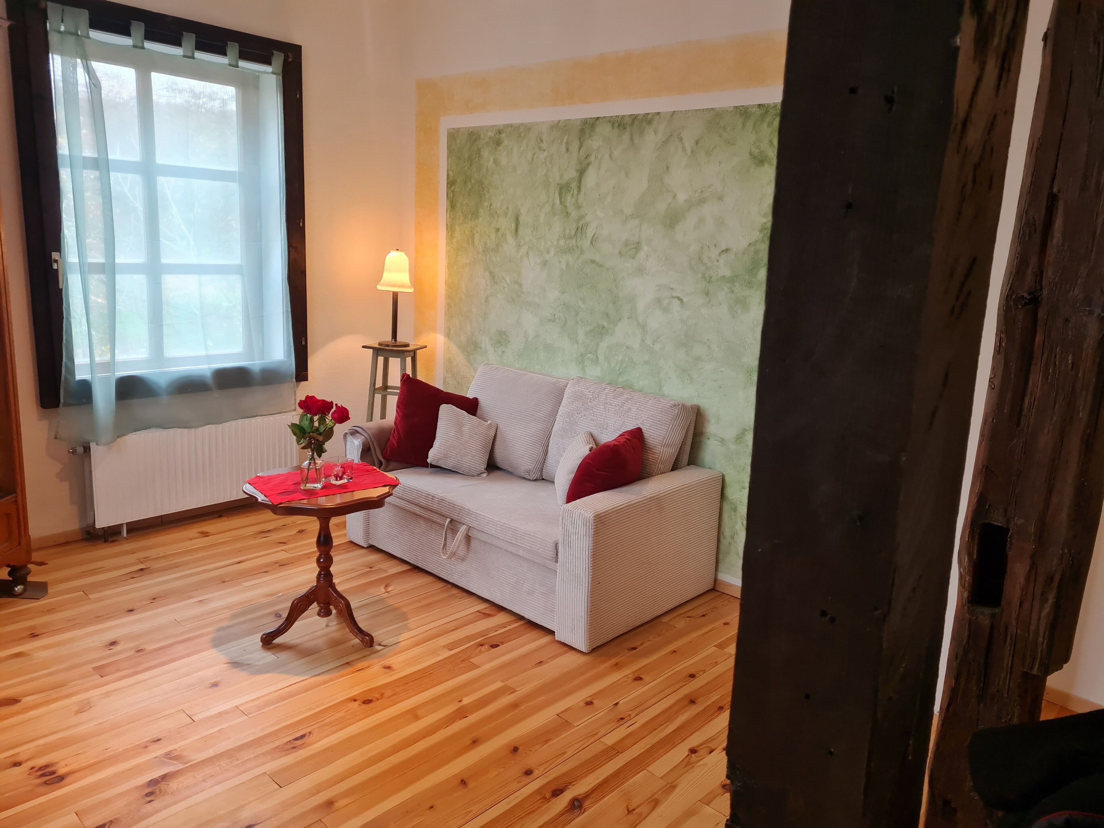 Een gezellige woonkamer met een witte bank, een klein houten tafeltje en een lamp.