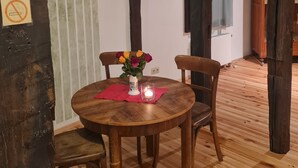 Ein Holztisch mit Stühlen, eine Vase mit Blumen und eine Kerze.