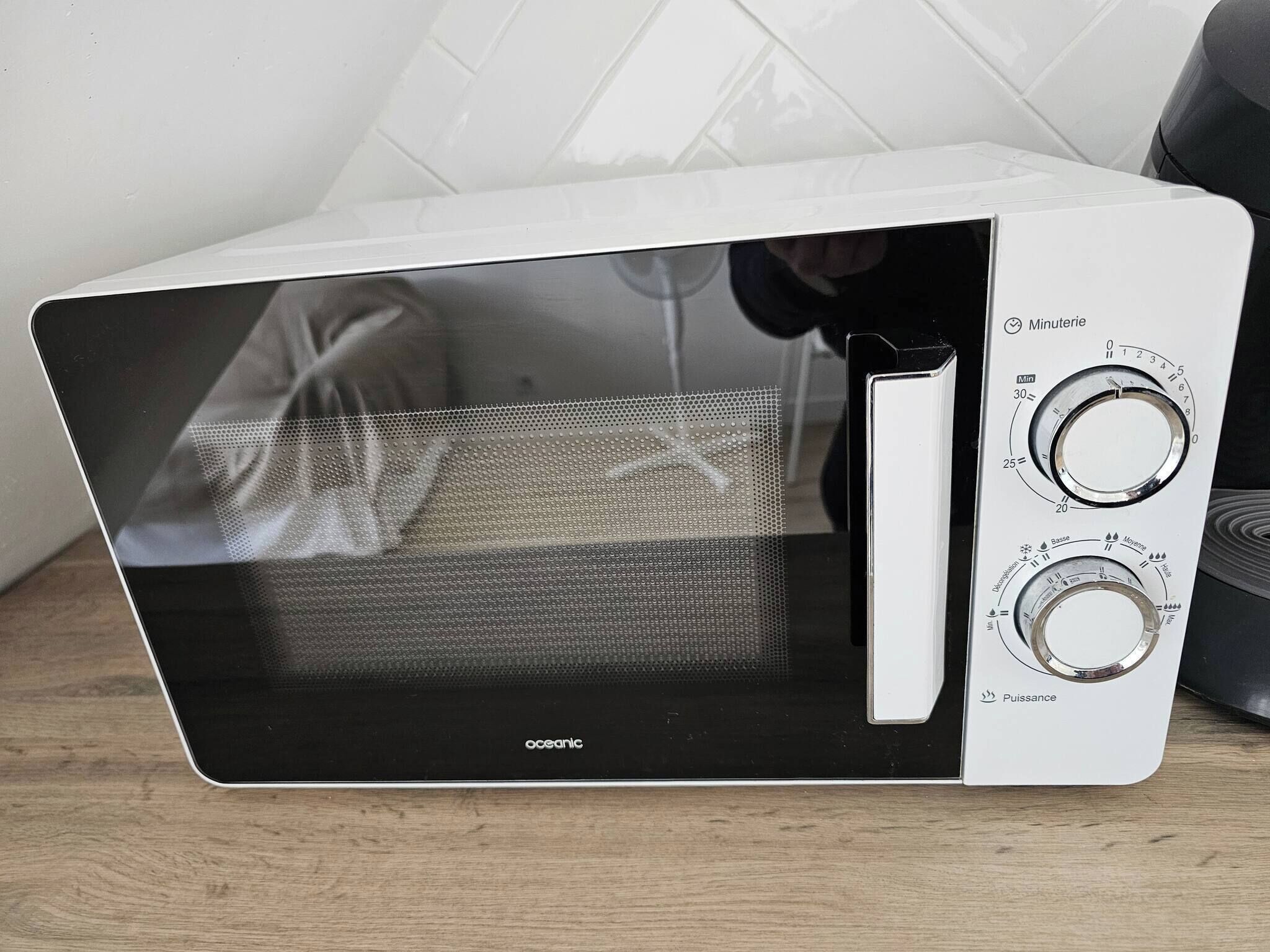 Un forno a microonde bianco con display digitale e due manopole.