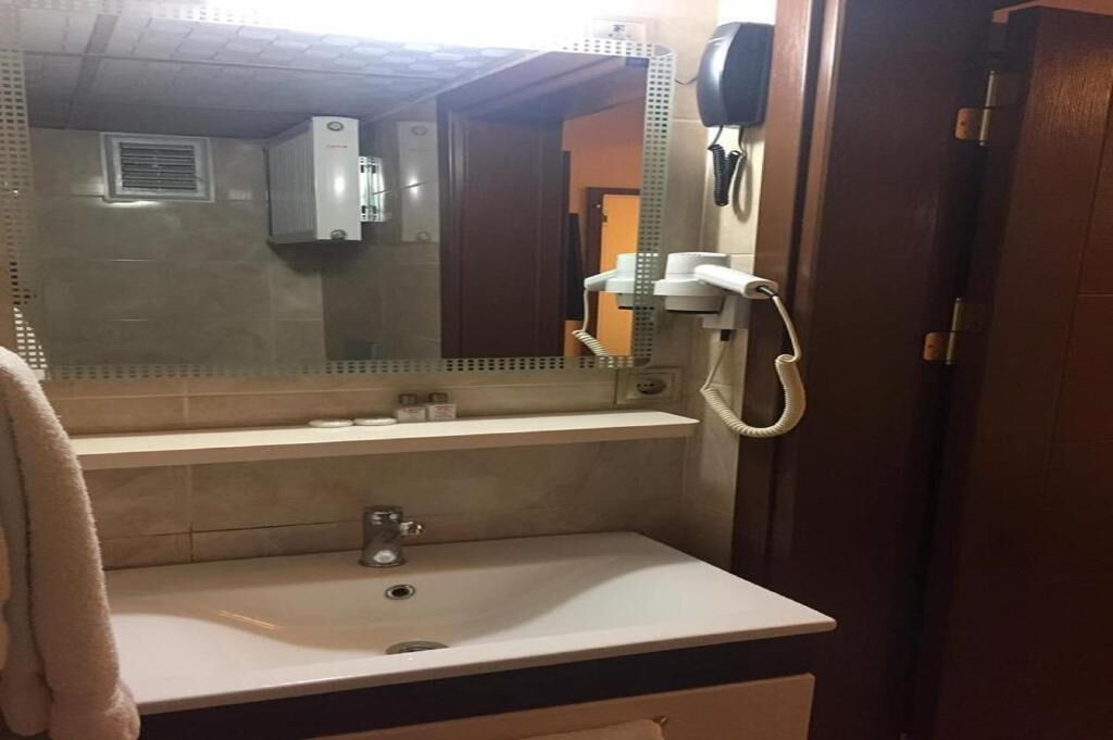 A bathroom with a sink, mirror, towel rack, and a hairdryer.