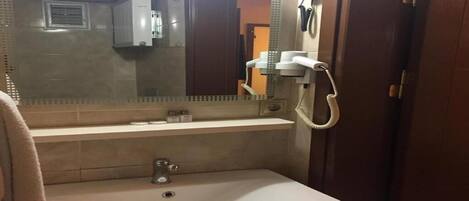 A bathroom with a sink, mirror, towel rack, and a hairdryer.