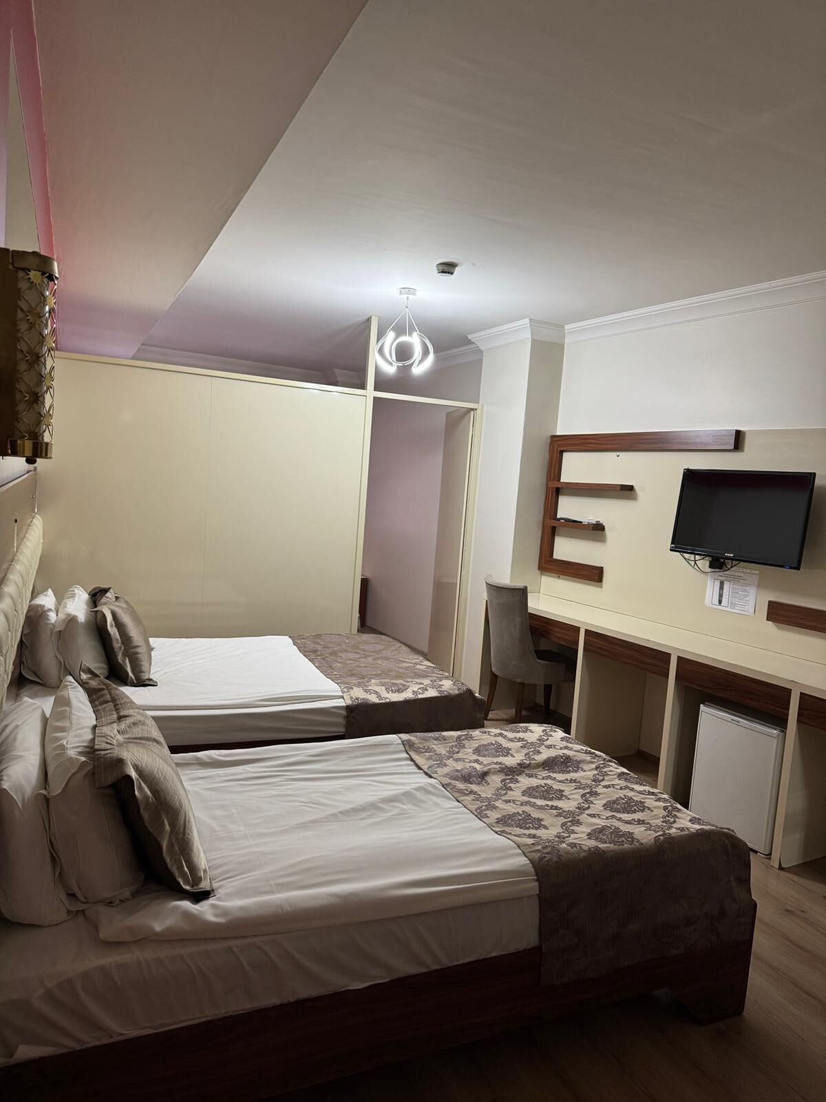 Un dormitorio con dos camas, un escritorio, un televisor y un armario.