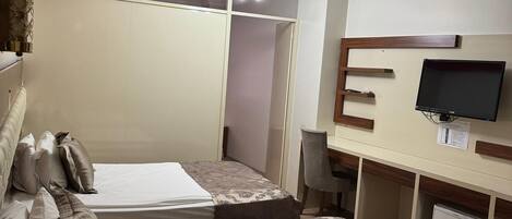 Un dormitorio con dos camas, un escritorio, un televisor y un armario.