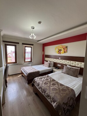 Ett hotellrum med två sängar, en röd accentvägg, en taklampa och ett fönster med utsikt.
