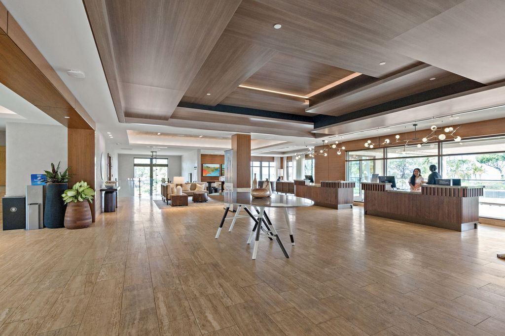 A spacious lobby with a reception desk, seating area, and large windows.