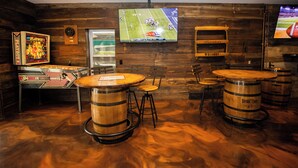 Zona de bar amb bótes de fusta, televisió que mostra un partit de futbol i una revista Playboy penjada a la paret.