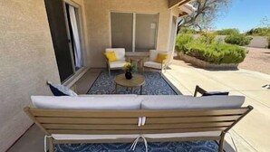 A covered patio area with a sofa, chairs, and a small table. - Comfy-cozy 1BR home in gated 55+ community (Goodyear)