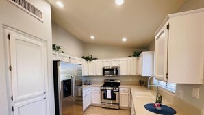 A kitchen with white cabinets, stainless steel appliances, a microwave, and a sink. - Comfy-cozy 1BR home in gated 55+ community (Goodyear)