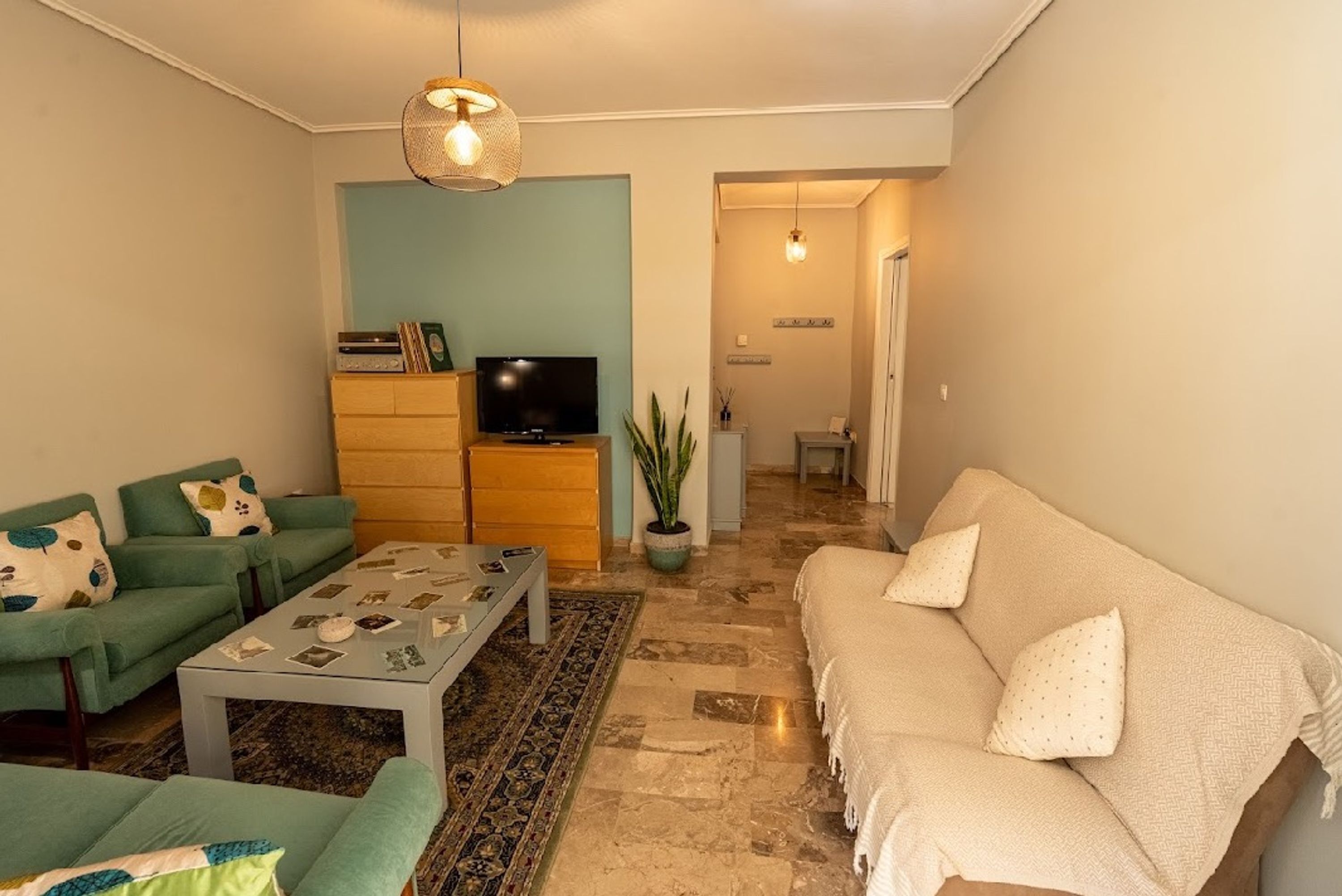 A living room with a sofa, a coffee table, a television, and a plant.