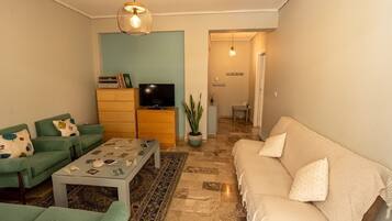 A living room with a sofa, a coffee table, a television, and a plant.