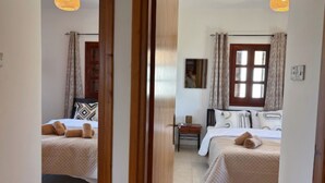 A bedroom with two beds, a window, and a nightstand. - St Visianos stone house (Filousa)
