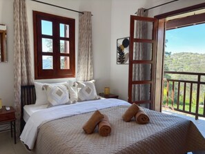 A bedroom with a bed, a window, a door, and a view of the outdoors. - St Visianos stone house (Filousa)