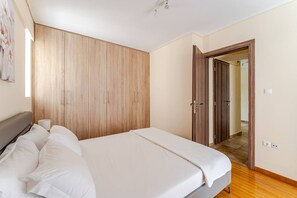 A bedroom with a bed, wooden wardrobe, and a door leading to another room. - LUX & STYLE 75sqm IN ATHENS-PRIVATE PARKING (Athina)