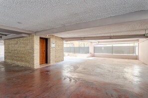 An empty interior with a brick wall, a wooden door, and a garage with a metal shutter. - LUX & STYLE 75sqm IN ATHENS-PRIVATE PARKING (Athina)
