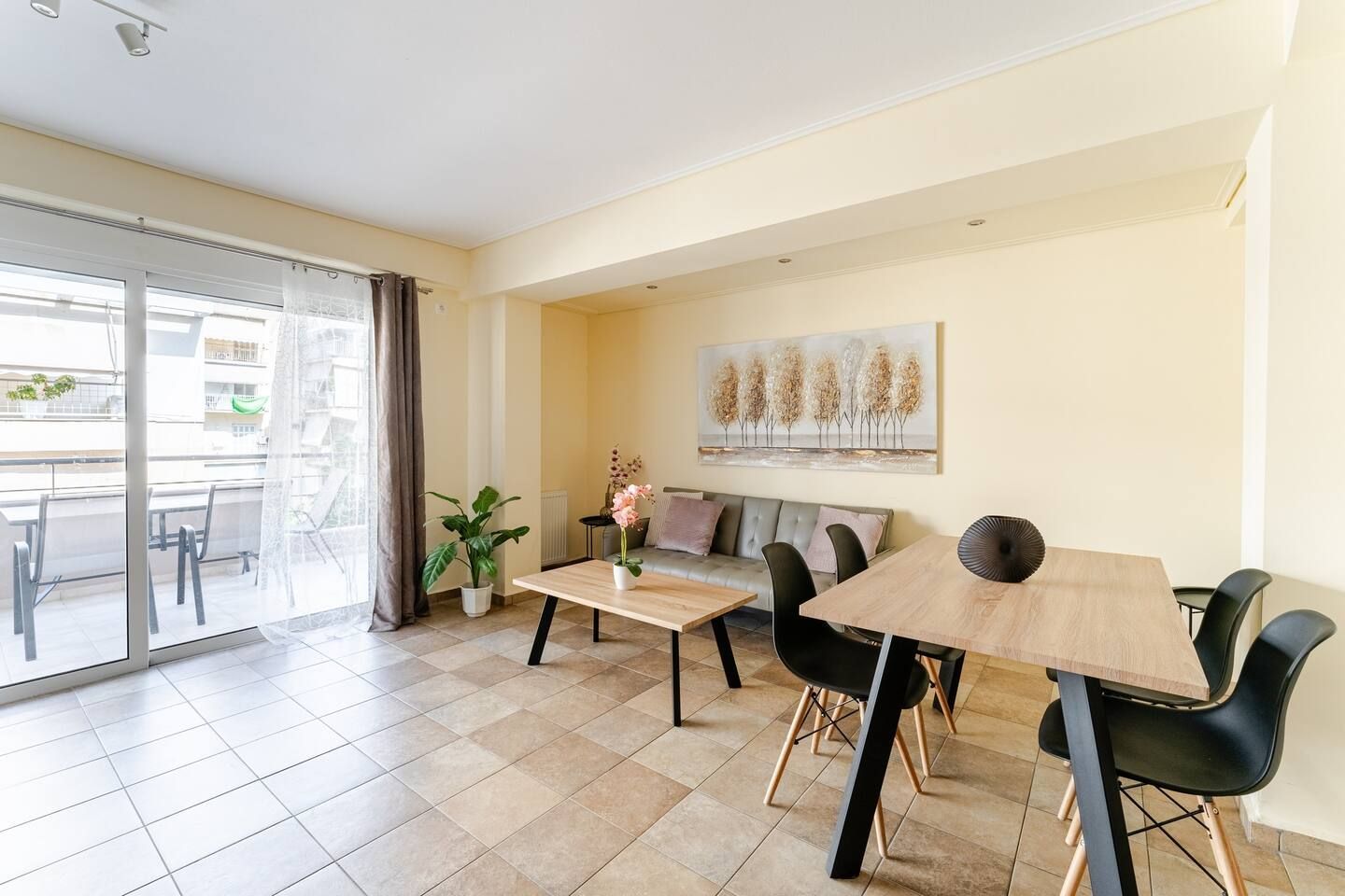A modern dining area with a table, chairs, a sofa, and a potted plant.