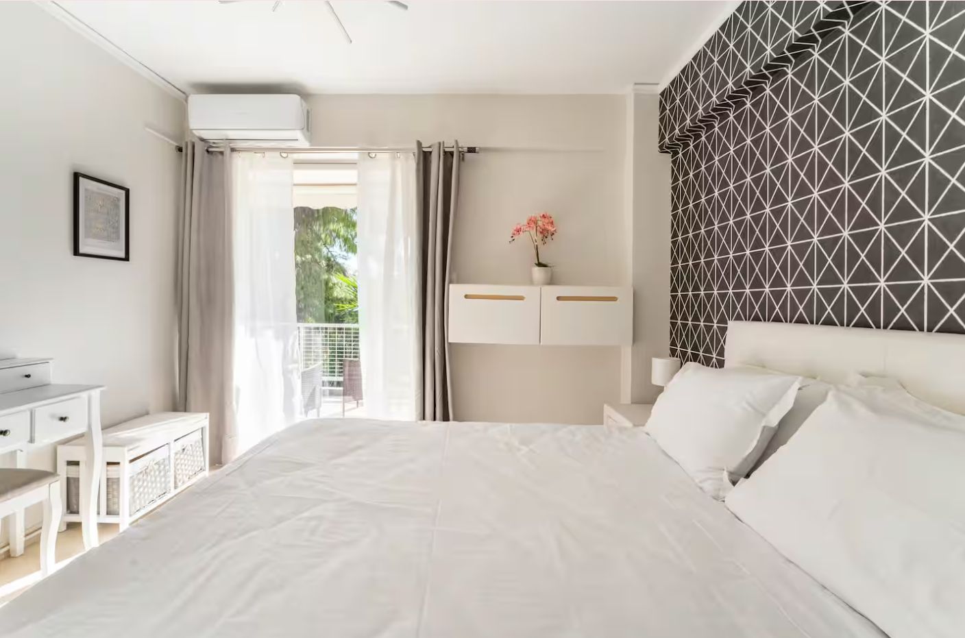 Een slaapkamer met een bed, nachtkastjes, een bureau en een raam met gordijnen.