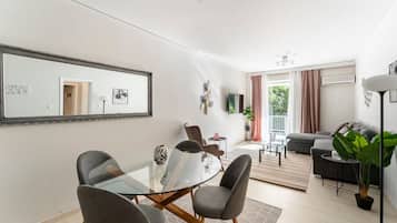 A modern living space with a dining area, a sofa, and a large mirror.