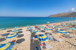 A beach with numerous umbrellas and sun loungers.